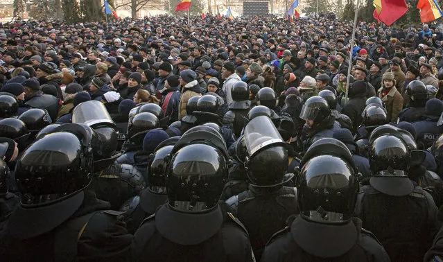 Riot police officers stand in line in front of protesters, some wanting closer links to Russia, others demanding a crackdown on corruption, outside the parliament in Chisinau, Moldova, Thursday, January 21, 2016. Moldova's new pro-European government has been sworn in, after protesters stormed Parliament and scuffled with police following a vote that ended a standoff between the president and the legislature. (Photo by Roveliu Buga/AP Photo)