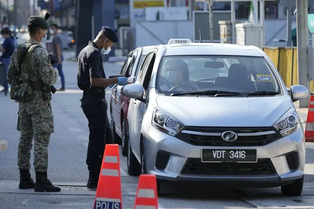 Police check passengers in vehicles at a roadblock during the first day of Full Movement Control Order (MCO) in Kuala Lumpur, Malaysia, Tuesday, June 1, 2021. Malls and most businesses in Malaysia shuttered Tuesday as the country began its second near total coronavirus lockdown to tackle a worsening pandemic that has put its healthcare system on the verge of collapse. (Photo by Vincent Thian/AP Photo)