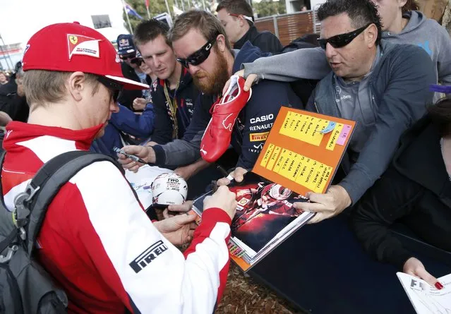Ferrari Formula One driver Kimi Raikkonen of Finland (L) signs autographs as he arrives for the first practice session of the Australian F1 Grand Prix at the Albert Park circuit in Melbourne March 13, 2015. REUTERS/Brandon Malone