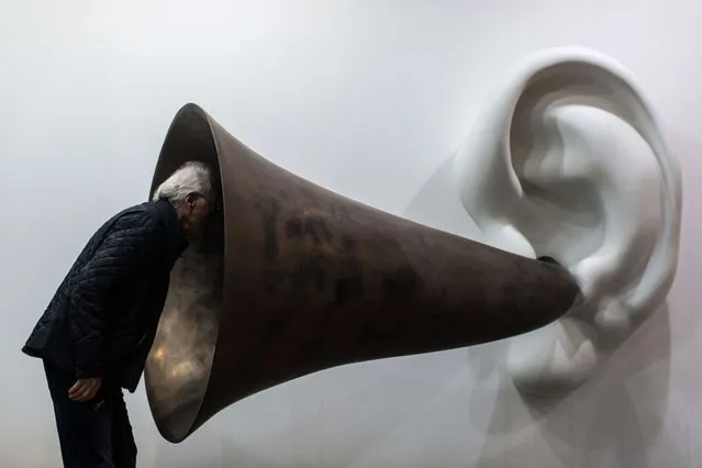 A visitor peers into US artist John Baldessari's “Beethoven's Trumpet (With Ear) Opus # 133” at the Art Basel fair in Hong Kong on March 15, 2015. Hong Kong's biggest art fair, Art Basel, opened its doors with thousands of visitors expected for a city-wide canvas of creativity and commerce. (Photo by Anthony Wallace/AFP Photo)