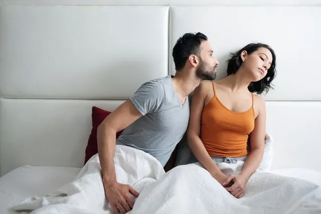 Angry woman refusing reconciliation with man after fight in bed. Upset wife during her period and husband trying to kiss her. Relationship problems for married couple. (Photo by Diego Cervo/Rex Features/Shutterstock)