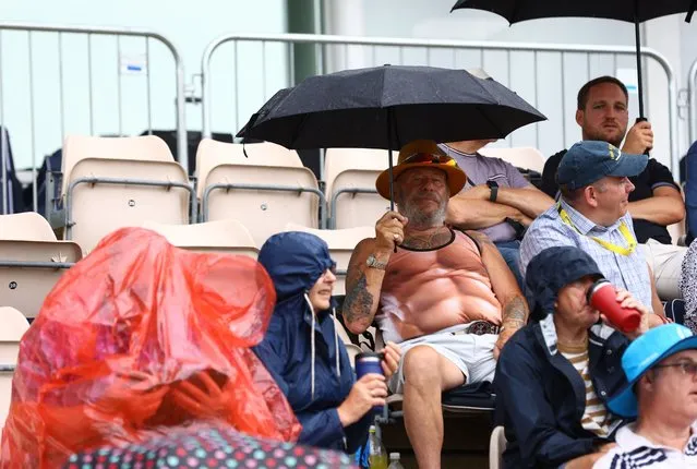 Spectators shelter from a cloudburst before the delayed start of the second one-day cricket international between England and New Zealand at Southampton, Britain on September 10, 2023. England levelled the series with a 79-run win. (Photo by Paul Childs/Action Images via Reuters)