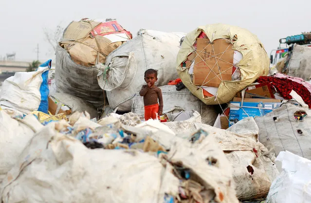 A boy stands on a sack of discarded plastic goods at a recycling yard in New Delhi, India, November 22, 2018. (Photo by Adnan Abidi/Reuters)