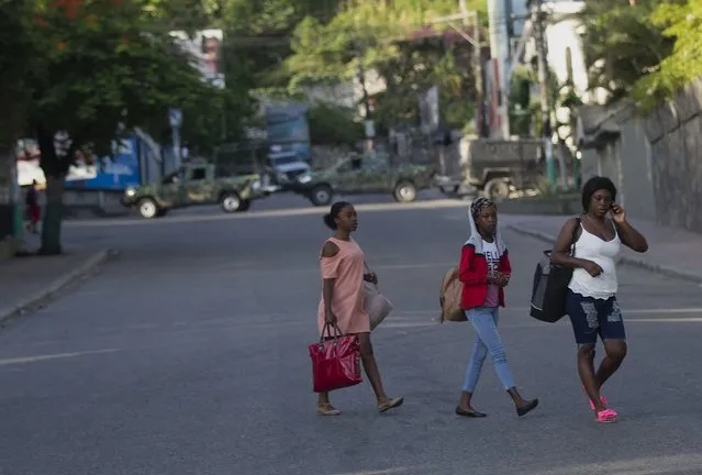 People walk past military vehicles blocking the entrance to Petion Ville, the neighborhood where the late Haitian President Jovenel Moise lived in Port-au-Prince, Haiti, Wednesday, July 7, 2021. (Photo by Joseph Odelyn/AP Photo)