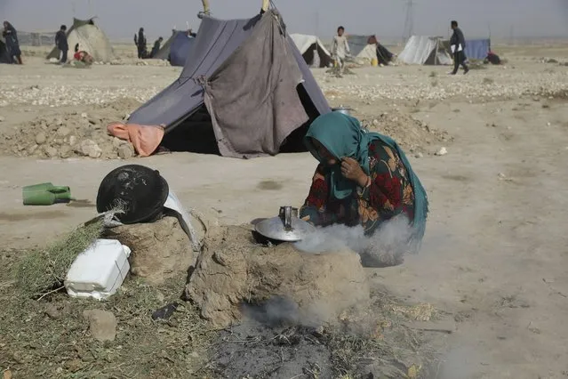 An internally displaced Afghan woman who fled her home due to fighting between the Taliban and Afghan security personnel, burns thorny twigs to make tea in a makeshift tent camp on a rocky patch of land on the edge of the city of Mazar-e-Sharif, northern Afghanistan, Thursday, July 8, 2021. (Photo by Rahmat Gul/AP Photo)