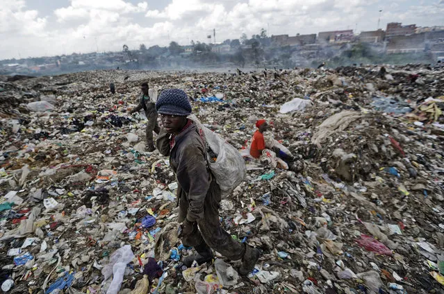 In this photo taken Wednesday, December 5, 2018, a man who scavenges for pieces of plastic for a living walks across a mountain of garbage at the dump in the Dandora slum of Nairobi, Kenya. (Photo by Ben Curtis/AP Photo)