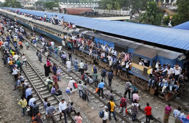 Bangladeshi Muslims sit atop a train and others wait at a station to head back to their hometowns ahead of the Muslim holiday of Eid al-Adha, in Dhaka, Bangladesh, Tuesday, September 8, 2016. (Photo by A.M. Ahad/AP Photo)