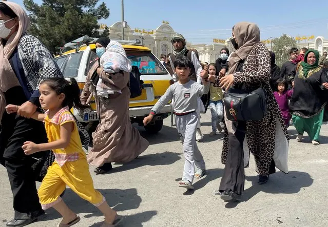 Women with their children try to get inside Hamid Karzai International Airport in Kabul, Afghanistan on August 16, 2021. (Photo by Reuters/Stringer)