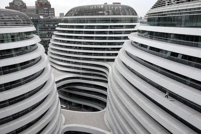 A worker cleans an exterior of a newly built urban complex building accommodating offices and retail shops in Beijing October 14, 2013. (Photo by Kim Kyung-Hoon/Reuters)