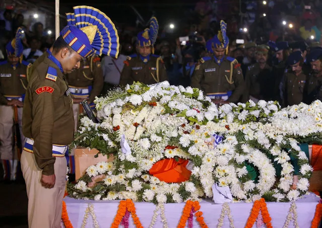 Central Reserve Police Force (CRPF) officers bow to pay tribute next a coffin containing the remains of their colleague Bablu Santra, who was killed after a suicide bomber rammed a car into the bus carrying CRPF personnel in south Kashmir on Thursday, before his cremation at Bauria village in Howrah district in West Bengal, India, February 16, 2019. (Photo by Rupak De Chowdhuri/Reuters)