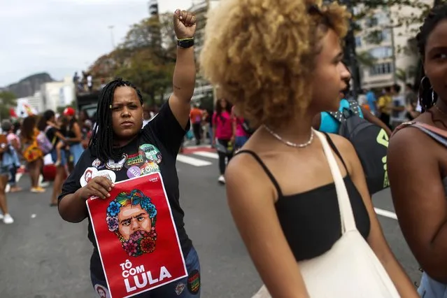 A woman raises her fist while holding a sign with a visage of then former President Luiz Inacio Lula da Silva during a Black Women's March in Rio de Janeiro, Brazil, July 31, 2022. Demands for reparations for Brazil's role in slavery are being heard in public, partly a reflection of the political climate ushered in by Lula, who took office in January 2023. (Photo by Bruna Prado/AP Photo)