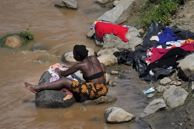 A woman who is part of a migrant caravan, washes her clothes on the banks of the in Huixtla River, Chiapas state, Mexico, Tuesday, October 26, 2021, on a day of rest before continuing their trek across southern Mexico to the U.S. border. (Photo by Marco Ugarte/AP Photo)
