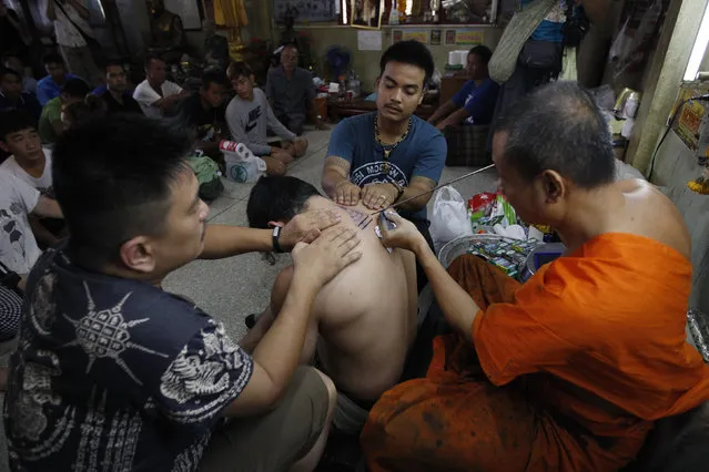 A Buddhist monk uses a traditional needle to tattoo the body of a man at Wat Bang Phra in Nakhon Pathom province on the outskirts of Bangkok, Thailand,  March 18, 2016. (Photo by Chaiwat Subprasom/Reuters)