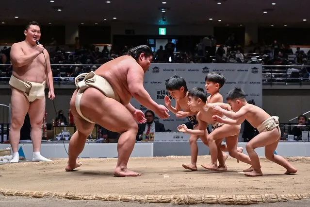 Retired Mongolian-born “yokozuna” wrestler Hakuho (far L), who now goes by the name Miyagino, watches as participants (R) try to push out Japanese wrestler Hakuoho (C) during a sumo class for youngsters on the sidelines of the 14th Hakuho Cup, a competition for young sumo wrestlers from elementary and middle school, at the Kokugikan arena in the Ryogoku area of Tokyo on February 12, 2024. (Photo by Richard A. Brooks/AFP Photo)