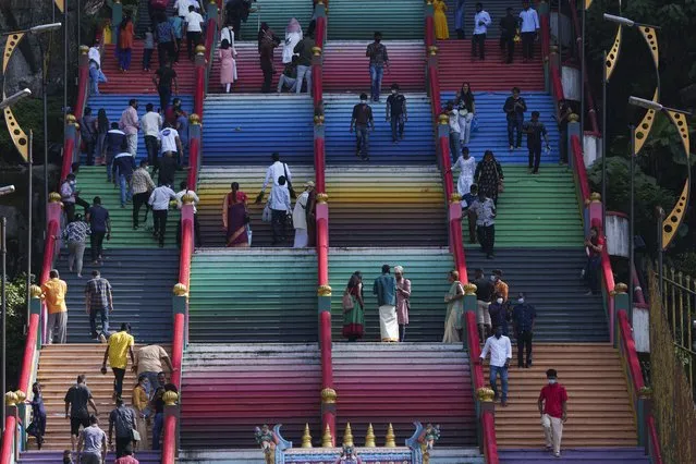 Hindu devotees climb the colored stairs to pray at the Batu Caves temple during the Hindu festival of lights, Diwali, in Kuala Lumpur, Malaysia, Thursday, November 4, 2021. Diwali is one of Hinduism's most important festivals, dedicated to the worship of the goddess of wealth Lakshmi. (Photo by Vincent Thian/AP Photo)