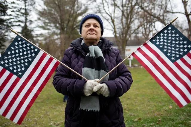 A supporter holding American flags listens to speakers as people gather to attend a “Let's Go Brandon Festival” rally, promoted by the Michigan Conservative Coalition and in opposition to U.S. President Joe Biden, in the Brandon Township village of Ortonville, Michigan, U.S. November 20, 2021. (Photo by Emily Elconin/Reuters)