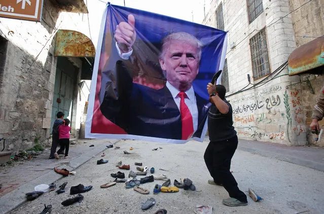 A Palestinian demonstrator throws an old shoe at a poster of US President Donald Trump as they protest against his support of Israel and demand for the Israeli army to re- open Shuhada Street, which is largely closed off to Palestinians, near a Jewish settler enclave in the heart of the flashpoint West Bank city of Hebron on February 24, 2017. (Photo by Hazem Bader/AFP Photo)