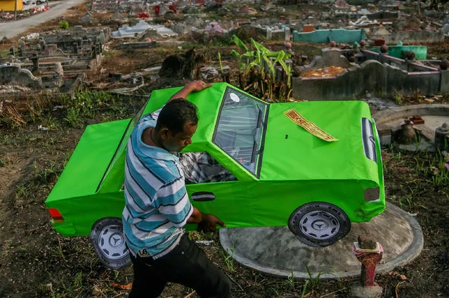 A man carries a replica Mercedes Benz car made from paper at grave site before the Qing Ming Festival on April 4, 2016 in Shah Alam, Malaysia. Qingming, also known as Tomb-Sweeping Day, on that day people will coming to cleaning the tomb and paying respect to the dead person with offerings their ancestors. This festivals will celebrated on April 4-6 every year. (Photo by Mohd Samsul Mohd Said/Getty Images)