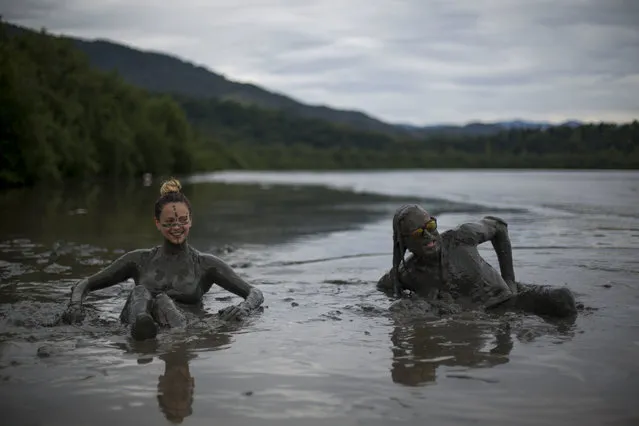 Chilean tourists Michele Yoyo and her husband Rodrigo Yoyo wade in a mud puddle during the traditional “Bloco da Lama” or “Mud Street” carnival party, in Paraty, Brazil, Saturday, February 25, 2017. Legend has it the “bloco” was born in 1986 after local teens hiking in a nearby mangrove forest smeared themselves with mud to discourage mosquitoes and then wandered through Paraty. The party grew year after year, but revelers eventually were banned from parading in the colonial downtown after shopkeepers complained pristine white walls were stained with the hard-to-remove mud. (Photo by Mauro Pimentel/AP Photo)