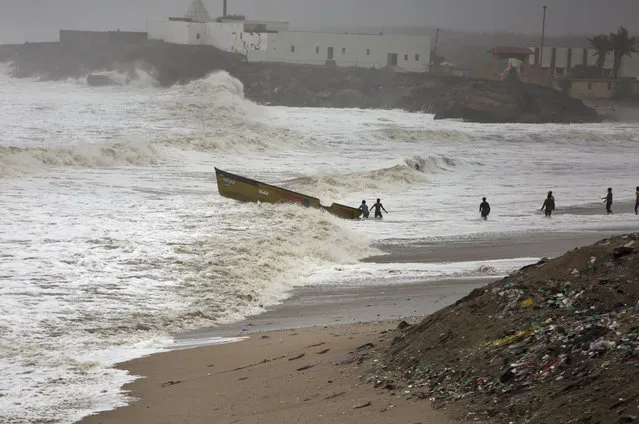 People try to pull back a fishing boat that was carries away by waves on the Arabian Sea coast in Veraval, Gujarat, India, Thursday, June 13, 2019. (Photo by Ajit Solanki/AP Photo)