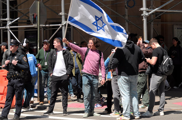 A pro-Israel protester waves an Israeli flag across the street from a pro-Palestine demonstration New York University. Pro-Palestine demonstrators rallied at New York University in Manhattan, New York City condemning the Israel Defense Forces' military operations in Gaza. Since Monday morning, students and pro-Palestine activists at NYU have held a sit-in protest on campus, forming a "Gaza Solidarity Encampment." The NYU encampment follows a similar encampment that began in Columbia University in New York City less than a week ago. Encampments have been forming in other universities nationwide in support of Palestine. Since the war started on October 7, 2023, Gaza's health ministry said more than 34,000 people have been killed in Gaza, a territory ruled by Hamas. The death toll does not differentiate between civilians and combatants. (Photo by Jimin Kim/SOPA Images/Rex Features/Shutterstock)