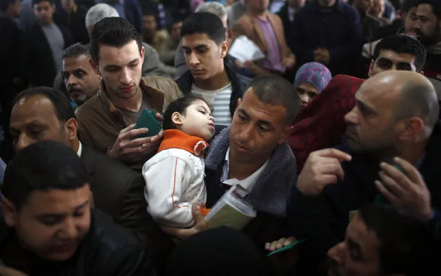 A Palestinian man carries a sleeping girl as he waits with other Palestinians hoping to cross into Egypt to register their names at the Rafah crossing between Egypt and the southern Gaza Strip March 29, 2014. Egyptian authorities partially reopened Rafah border crossing, Gaza's main window to the world, on Saturday for three days after 50 days of its closure, Palestinian border officials said. Since the overthrow of Egyptian President Mohamed Mursi in July 2013. (Photo by Mohammed Salem/Reuters)