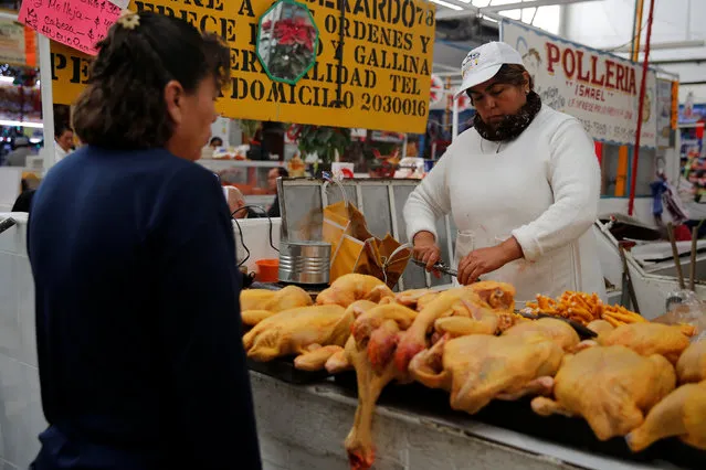 A woman cuts chicken for a customer at her stall in Granada market in Mexico City, Mexico, January 10, 2017. (Photo by Tomas Bravo/Reuters)