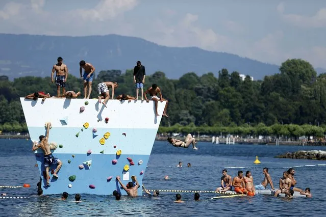 A group of swimmers play on a climbing wall in the water of the Bains des Paquis on a hot summer day in Geneva, Switzerland, July 1, 2015. (Photo by Pierre Albouy/Reuters)