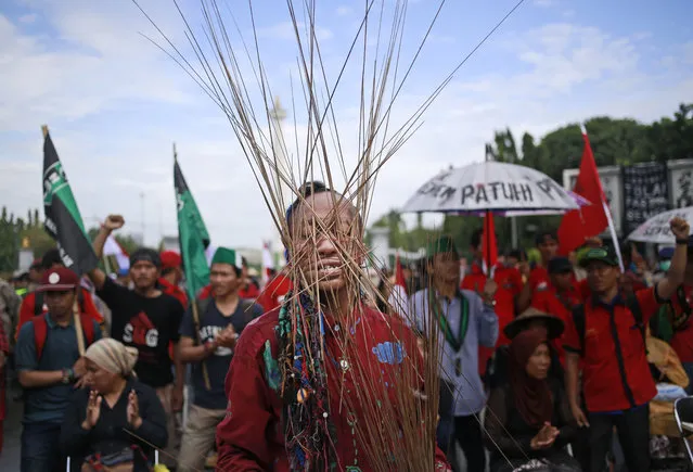In this March 20, 2017 photo, an activist has skewers wrapped around his head with rubber bands during a rally against the operation of a cement factory in Kendeng, West Java, outside the presidential palace in Jakarta, Indonesia. Kendeng farmers have battled against plans for the factory for years, saying it could taint their water. The factory is now more or less complete and the owner, state-owned PT Semen Indonesia, has said it would create jobs and boost the local economy. (Photo by Dita Alangkara/AP Photo)