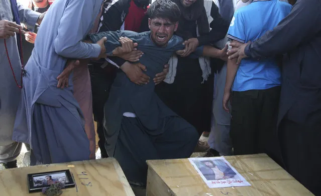 A relative wails near the coffins of victims of the Dubai City wedding hall bombing during a mass funeral in Kabul, Afghanistan, Sunday, August18, 2019. The deadly bombing at the wedding in Afghanistan's capital late Saturday that killed dozens of people was a stark reminder that the war-weary country faces daily threats not only from the long-established Taliban but also from a brutal local affiliate of the Islamic State group, which claimed responsibility for the attack. (Photo by Rafiq Maqbool/AP Photo)