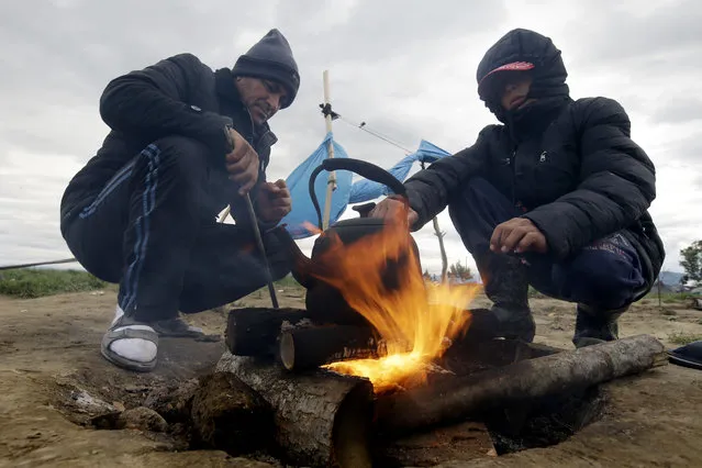 Aded Rahim, left, and Mohammed Aziz, both from Syria, stand by a fire at at the northern Greek border point of Idomeni, Greece, Wednesday, May 4, 2016. European Union countries that refuse to accept refugees under proposals to overhaul the EU's failed asylum laws could face large fines for each asylum seeker rejected. (Photo by Gregorio Borgia/AP Photo)