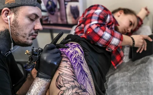 A tattoo artist applying ink on a girl' s thigh during the 2017 Moscow Tattoo Festival at Moscow' s Amber Plaza Shopping Center in Moscow, Russia on April 1, 2017. (Photo by Valery Sharifulin/TASS)