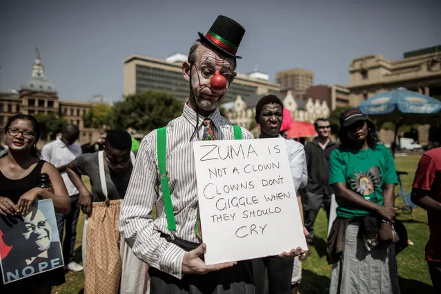 A man dressed up as a clown holds a placard during a rally outside the South African National Treasury on April 3, 2017, in Pretoria called by Save SA a coalition of civil organisations, opposition parties, Unions members and supporters to protest against South African president Jacob Zuma and his recent Cabinet re-shuffle. A memorial service on April 1, 2017 for anti-apartheid icon Ahmed Kathrada was transformed into a fierce attack on South African President Jacob Zuma, under fire after a controversial cabinet reshuffle. Party veterans of the ruling ANC, sacked finance minister Pravin Gordhan and Kathrada's widow lined up to criticise the state of the country as the crowd shouted “Zuma must go”. (Photo by Gianluigi Guercia/AFP Photo)