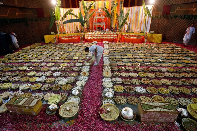 A Hindu priest spreads rose petals around different food items on the occasion of Ramnavmi festival inside a temple in Ahmedabad, India, April 5, 2017. (Photo by Amit Dave/Reuters)