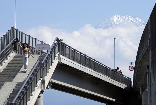 A foreign tourist walks down the stairs leading to the Fujisan Yumeno Ohashi, or “Mount Fuji Great Dream Bridge” as the Mount Fuji is seen in the background, in Fuji City, Shizuoka prefecture, central Japan, 08 June 2024. The Fujisan Yumeno Ohashi, or “Mount Fuji Great Dream Bridge”, is an overpass crossing a river, featuring a walkway separated from the road by a waist-high concrete wall. This location has gained popularity among foreign visitors due to its view of Mount Fuji, which has gone viral on social media. Tourists flock to the overpass stairs to take pictures that create the illusion of leading directly to Japan's highest peak. In response to the influx of foreign tourists, the municipality has installed a temporary toilet, opened a parking lot, and hired security guards. Due to safety concerns with visitors crossing the road to reach the center of the motorway, the local branch of the Ministry of Land, Infrastructure, Transport, and Tourism plans to install a 1.8-meter tall fence in July 2024 to prevent tourists from stepping into the middle of the road. (Photo by Franck Robichon/EPA)