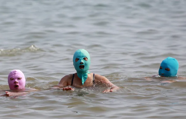 Women, wearing nylon masks, swim in the water during their visit to a beach in Qingdao, Shandong province July 6, 2012. (Photo by Aly Song/Reuters)