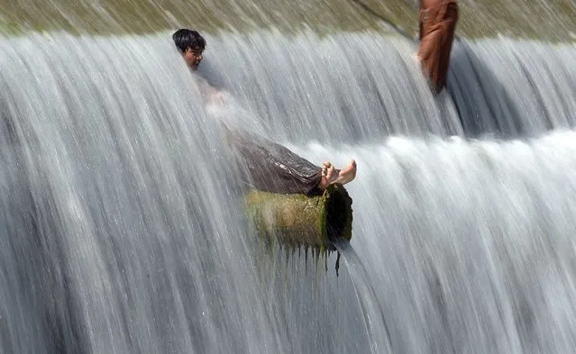 Pakistani youths cool off in a stream during hot weather on the outskirts of Islamabad on April 29, 2016. Pakistan's Meteorological Department has forecast hot and dry weather in most parts of the country with the highest temperatures recorded at 41 celsius in the southern Sindh province. (Photo by Aamir Qureshi/AFP Photo)