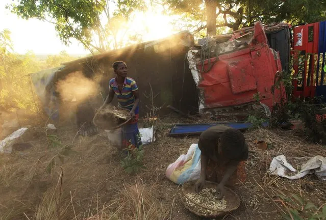 Women and children separate grain from soil, after the driver of a truck lost control of a vehicle which spilled grain, in the forest in Machinga, about 200 kilometers north east of Blantyre, Malawi, Tuesday, May 24, 2016. Hundreds of villagers thronged the spot and helped themselves to some of the grain. About 2.8 million Malawians – nearly 20 percent of the population – face food insecurity, making the country one of the worst hit in Southern Africa. (Photo by Tsvangirayi Mukwazhi/AP Photo)
