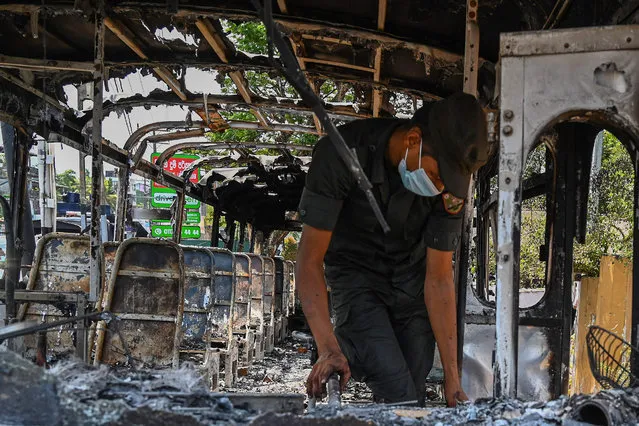 A soldier examines the charred out remains inside a burnt-out bus near Sri Lanka's President Gotabaya Rajapaksa's home in Colombo on April 1, 2022. Security forces were deployed across the Sri Lankan capital on April 1 after protesters tried to storm the president's home in anger at the nation's worst economic crisis since independence. (Photo by Ishara S. Kodikara/AFP Photo)