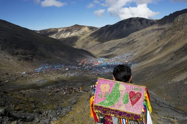 In this May 24, 2016 photo, a young boy descends the Qullqip'unqu mountain looking out at the tens of thousands of pilgrims gathered to celebrate the three-day festival Qoyllur Rit’i, translated from the Quechua language as Snow Star, in the Andean Sinakara Valley, in Peru's Cusco region. The celebration that mixes Catholic and indigenous beliefs honors Jesus as well as the area’s glacier, which is considered sacred among some indigenous people. While the native celebration is far older, the Christian part of the ritual stretches back to the 1700s, when Jesus is said to have appeared to a young shepherd in the form of another boy. (Photo by Rodrigo Abd/AP Photo)