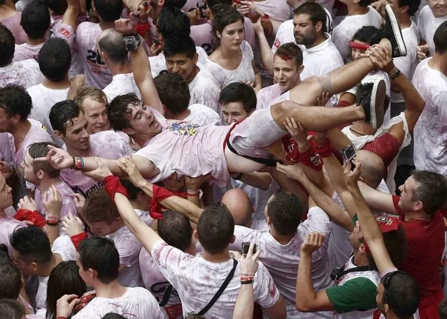 A man crowd surfs as thousands of revellers wait for the traditional “Txupinazo” rocket fire that marks the start of the Festival of San Fermin (or Sanfermines) at Consistorio square in Pamplona, Spain, 06 July 2014. (Photo by Javier Lizin/EFE)