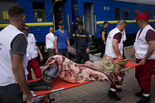An elderly patient is carried on a stretcher to board a medical evacuation train run by MSF (Doctors Without Borders) at the train station in Pokrovsk, eastern Ukraine, Sunday, May 29, 2022. The train is specially equipped and staffed with medical personnel, and ferries patients from overwhelmed hospitals near the front line, to medical facilities in western Ukraine, far from the fighting. (Photo by Francisco Seco/AP Photo)