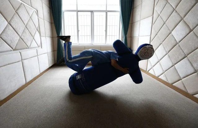 A recovering drug addict wrestles with a punching dummy to unleash pent-up anger during a psychological therapy at the Shiliping compulsory drug rehabilitation center in Longyou county, Zhejiang province, China, on June 19, 2014. Established in 2008, the center is one of the biggest in China in terms of numbers of inmates and facilities. Recovering drug addicts in the center are undergoing treatment with a strict regime in physical exercises, psychological therapies and medication, according to local media. (Photo by William Hong/Reuters)