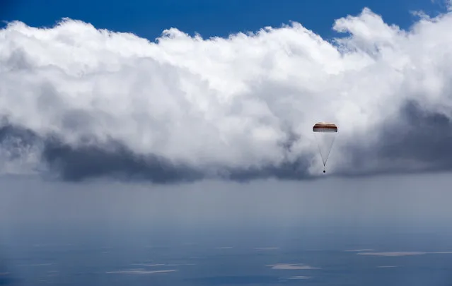 The Soyuz TMA-19M capsule carrying NASA's Tim Kopra, Tim Peake of the European Space Agency and Russian agency Roscosmos' Yuri Malenchenko descends beneath a parachute near the town of Dzhezkazgan, Kazakhstan, Saturday, June 18, 2016. A three-person crew from the International Space Station has landed safely in the sun-drenched steppes of Kazakhstan. (Photo by Shamil Zhumatov/Pool Photo via AP Photo)