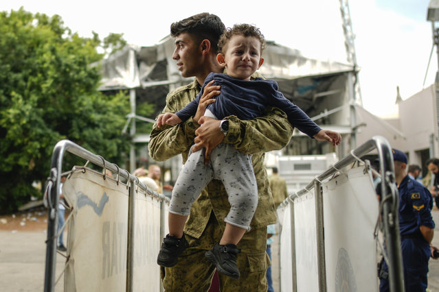 A Turkish military person carries a child on board of a Turkish military ship as he and hundreds of people, mostly Turkish citizens, are evacuated from Lebanon to Turkey, in Beirut port, on Thursday, October 10, 2024. (Photo by Emrah Gurel/AP Photo)