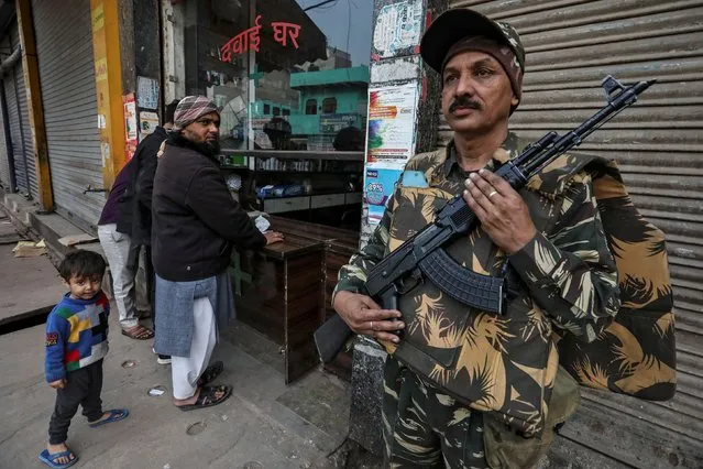 A paramilitary soldier stands guard outside a chemist shop at a riot affected area after clashes erupted between people demonstrating for and against a new citizenship law in New Delhi, February 28, 2020. (Photo by Rupak De Chowdhuri/Reuters)
