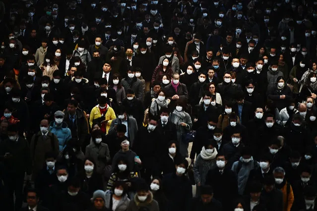 Mask-clad commuters make their way to work during morning rush hour at the Shinagawa train station in Tokyo on February 28, 2020. Tokyo's key Nikkei index plunged nearly three percent at the open on February 28 after US and European sell-offs with investors worried about the economic impact of the coronavirus outbreak. (Photo by Charly Triballeau/AFP Photo)