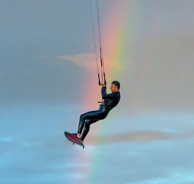 Standalone picture dated June 26, 2022 shows a kite surfer on Lytham St Anne's beach in Lancashire on June 26, 2022 jumping through a rainbow. (Photo by Mark McNeill/Bav Media)