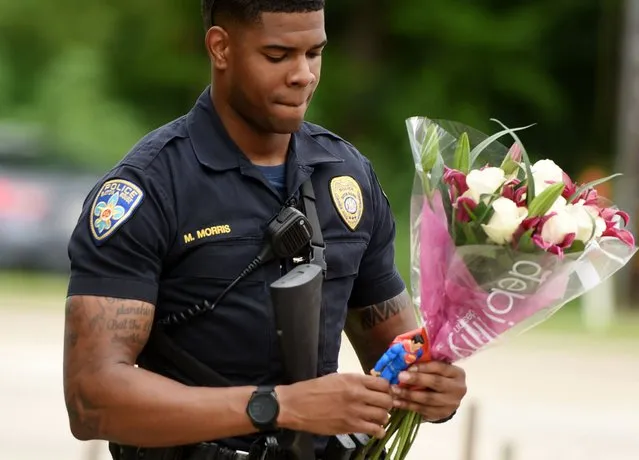 Baton Rouge Police Department Officer Markell Morris holds a bouquet of flowers and a Superman action figure that a citizen left at the Our Lady of the Lake Hospital where the police officers were brought this morning, Sunday, July 17, 2016. Multiple law enforcement officers were killed and wounded Sunday morning in a shooting near a gas station in Baton Rouge. (Photo by Henrietta Wildsmith/The Times via AP Photo)