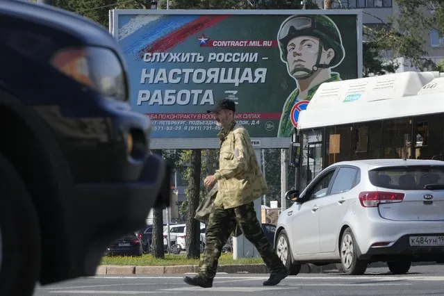 A man crosses a street past an army recruiting billboard with the words “Serving Russia is a real job!” in St. Petersburg, Russia, Saturday, August 20, 2022. Six months after Russia sent troops into Ukraine, there's little sign of the conflict on Moscow's streets and the capital's residents seem unconcerned about the economic and political sanctions by Western countries. (Photo by Dmitri Lovetsky/AP Photo)